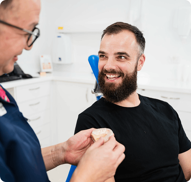 Dental professional discussing treatment with a smiling male patient in a clinical setting